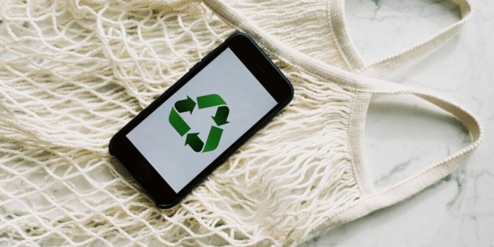 A smartphone displaying a recycle symbol on a mesh bag, promoting sustainability and eco-consciousness